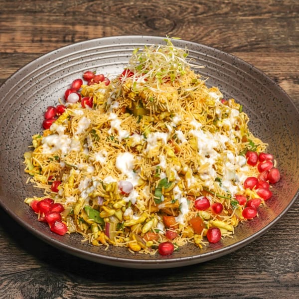Bhel Puri, an Indian street food, with puffed rice, vegetables, chutneys, and pomegranate seeds.